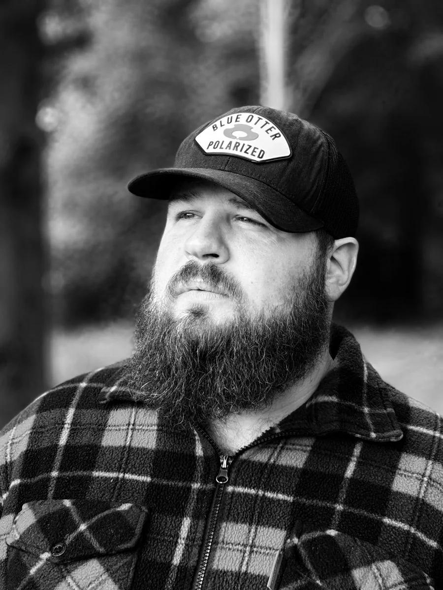 Black and white portrait of Adam Holland in a trucker cap